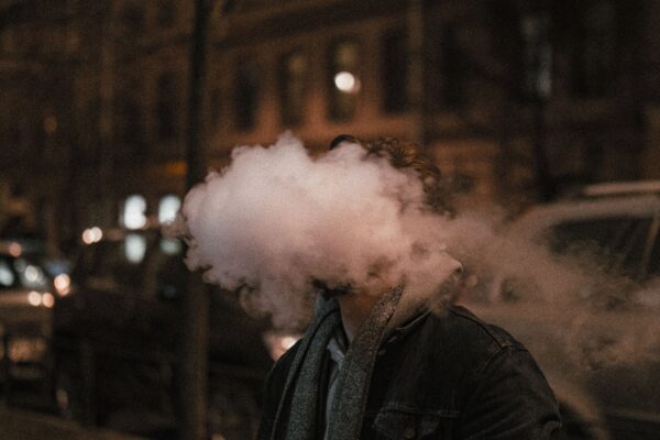 Man exhaling vapour at night, illustrating the vaping vs smoking cost UK comparison