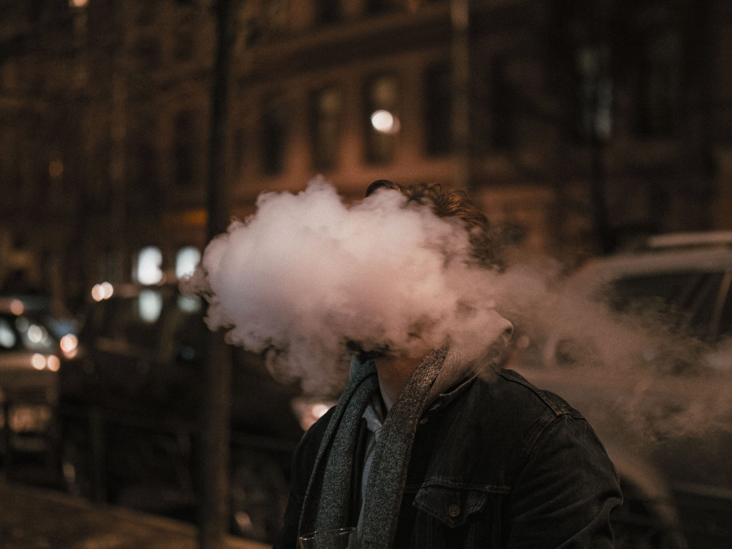 Man exhaling vapour at night, illustrating the vaping vs smoking cost UK comparison