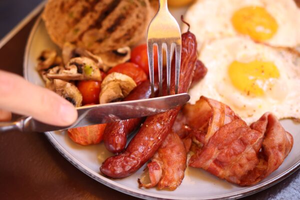 A full English breakfast with eggs, bacon, sausages, toast and tomatoes on a plate