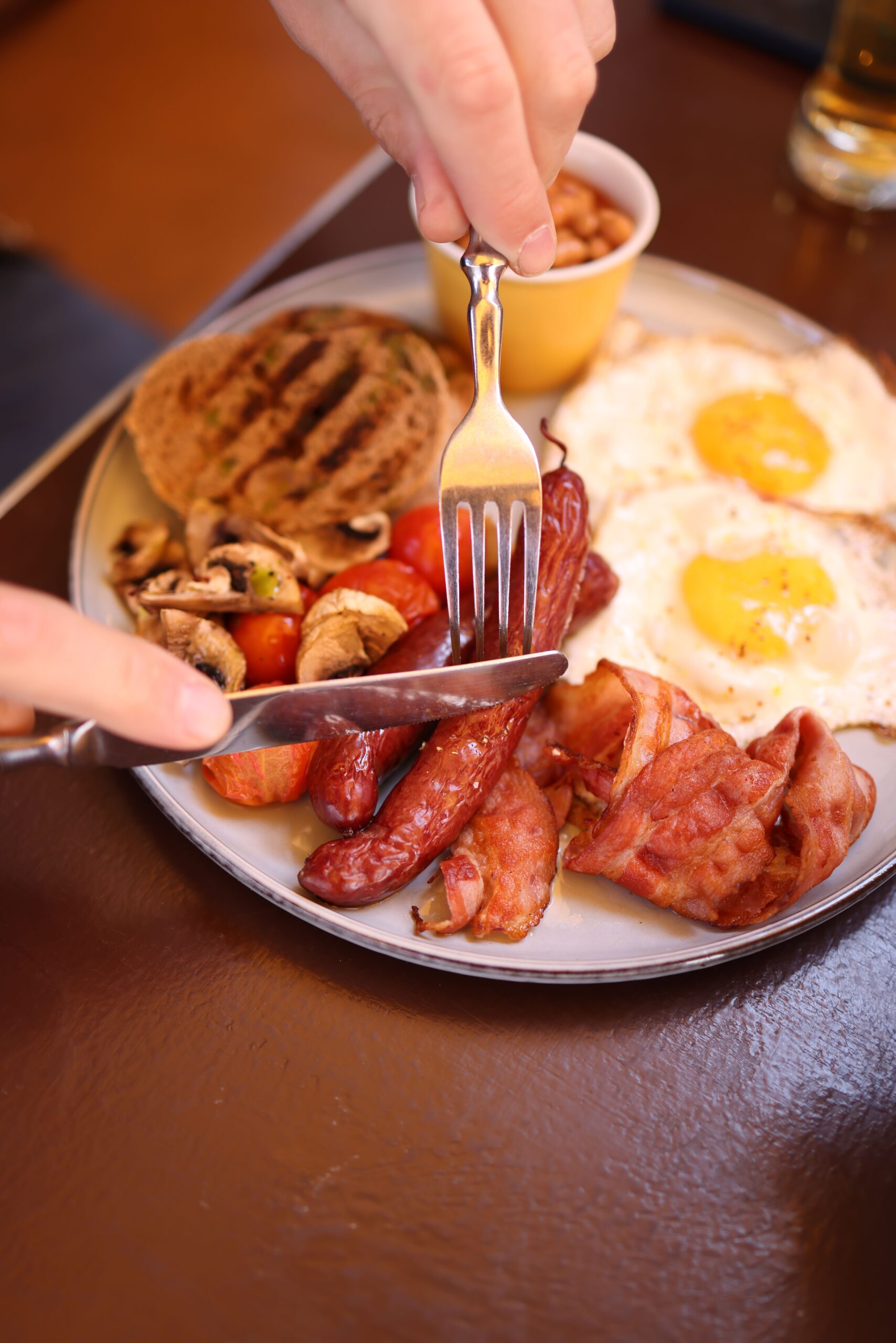 A full English breakfast with eggs, bacon, sausages, toast and tomatoes on a plate