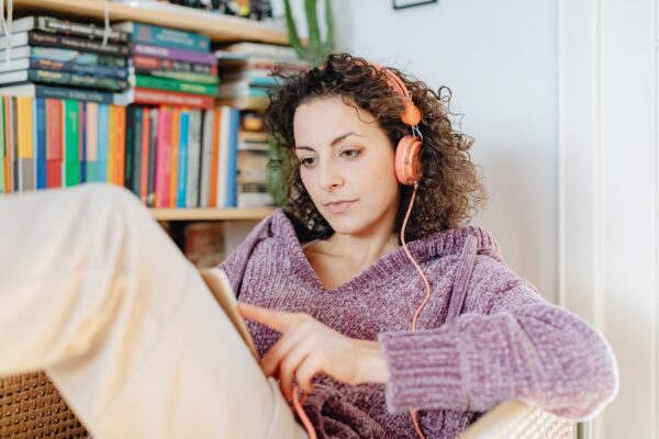 Woman relaxing with a book while listening to an audiobook through headphones