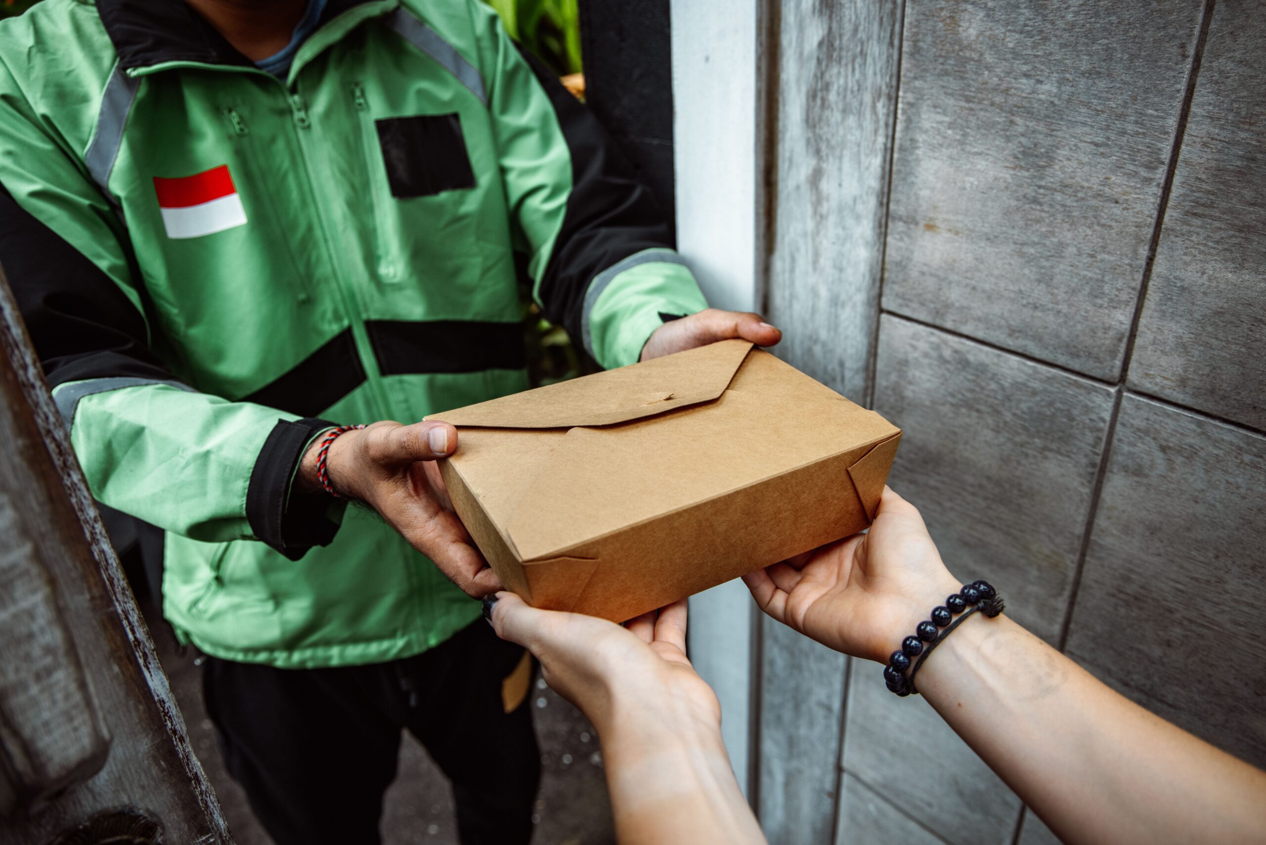 A delivery courier handing a food order to a customer at their door