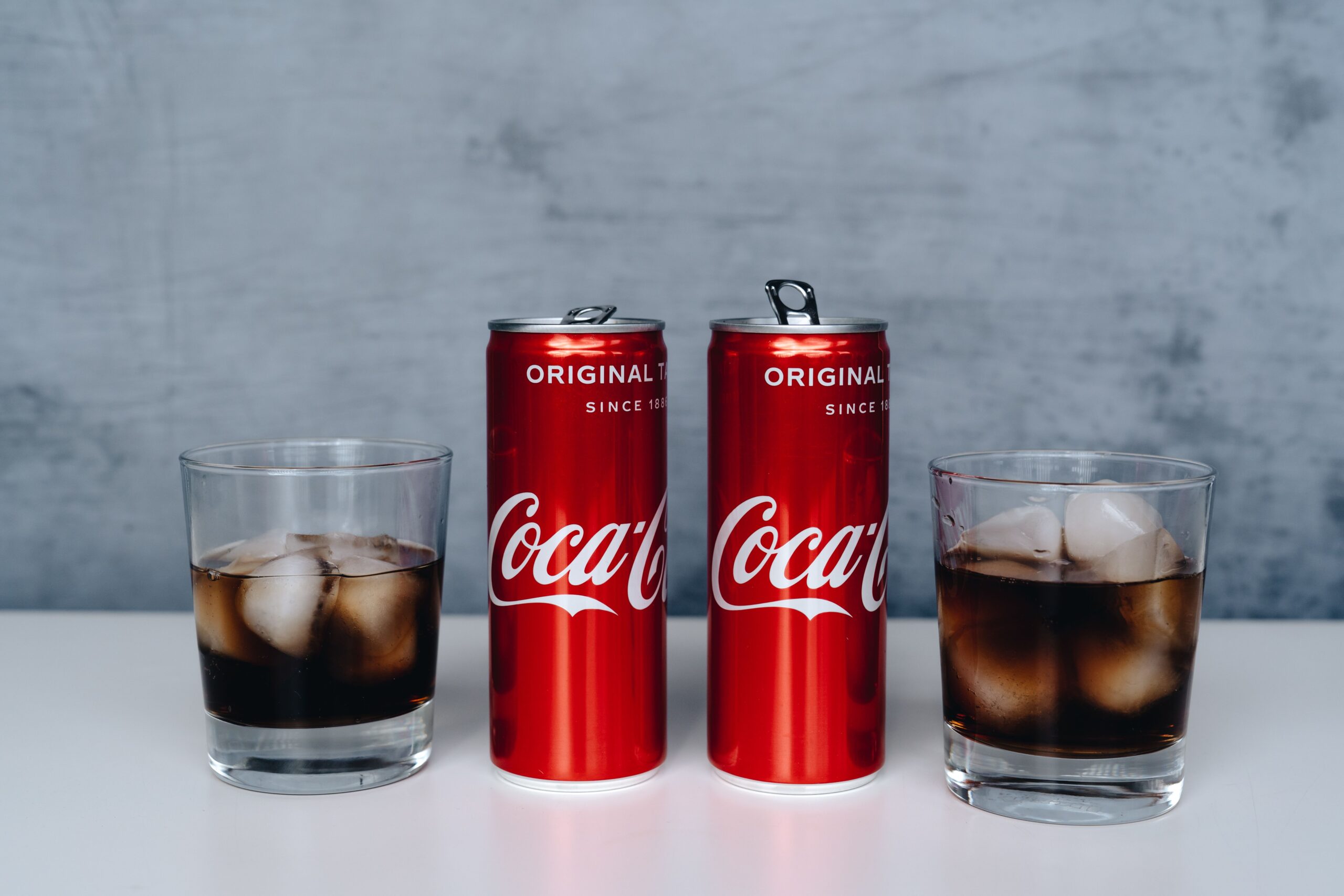 Canned cocktail price UK comparison - cola cans next to a poured drink over ice